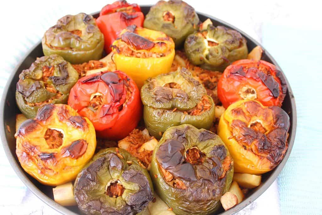 Albanian Stuffed Peppers - Picture shows a round baking tray with lots of stuffed bell peppers 