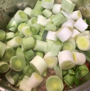 Adding leeks to browned meat and vegetables