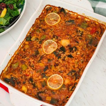 A casserole shown just baked on a counter, it's topped off with 3 lemon slices. This is a Mediterranean Leeks Casserole.