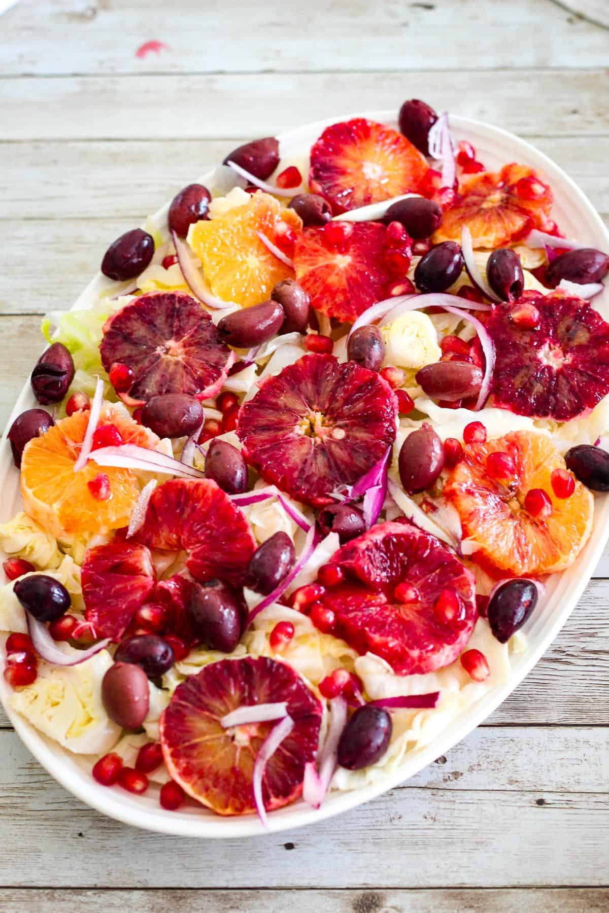 A cabbage salad with oranges and pomegranate seeds shown on a platter. 