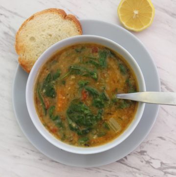 Instant Pot cooked yellow split peas soup with spinach, shown served in a soup bowl with bread and lemon