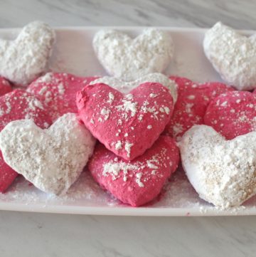 Valentine's Mediterranean Almond Cookies, white and pink heart shaped cookies covered in confectioner's sugar