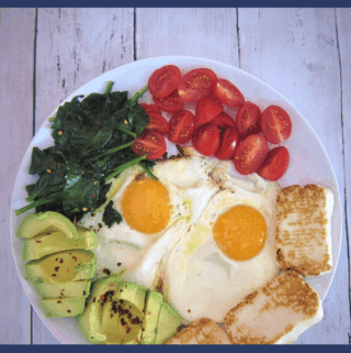 Low carb breakfast made with eggs, fried halloumi slices, spinach, avocado and tomatoes