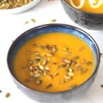 Leek soup with butternut squash and potatoes cooked in a pressure cooker, soup is garnished with pumpkin seeds. The other bowl of soup in the background is garnished with cream.