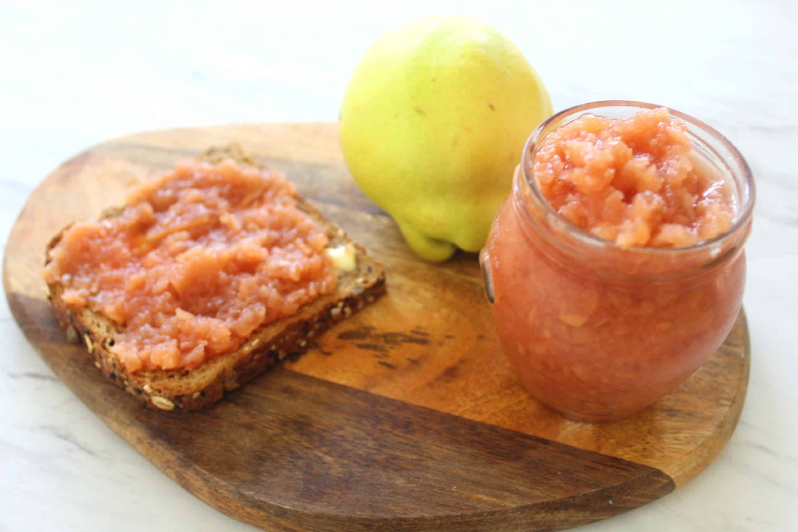 Quince jam jar, whole grain buttered toast layered with quince jam and a fresh quince shown all together.