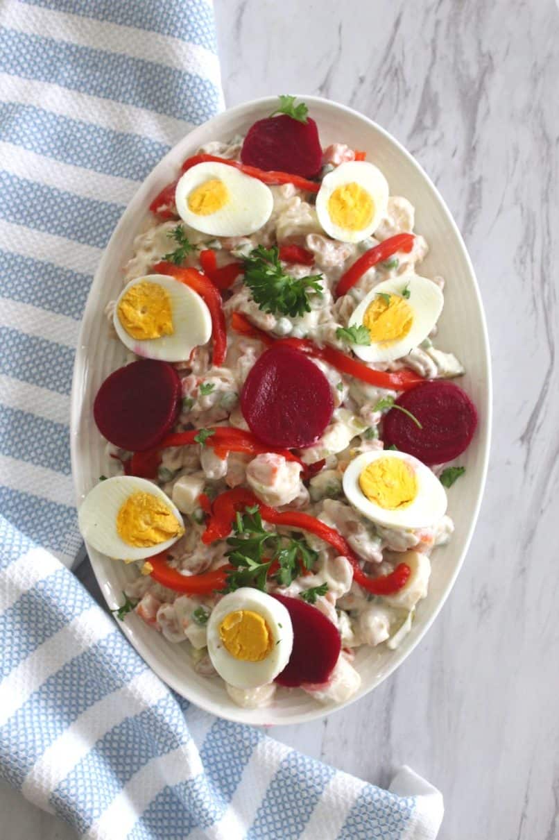 Albanian New Year's Eve Russian Salad - side dish showing a russian salad garnished with beets, eggs, roasted red peppers and parsley.