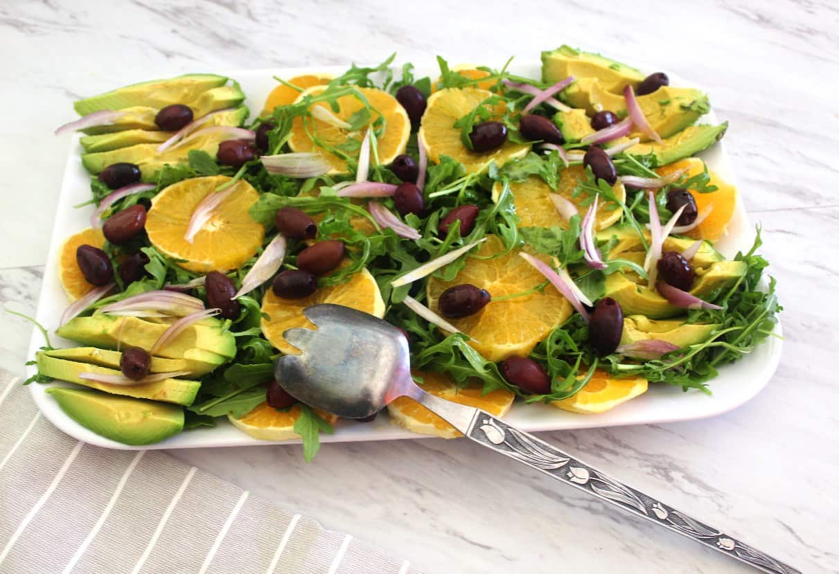 Orange salad with kalamata olives and red onions over arugula. This Mediterranean salad is served with an orange dressing. 