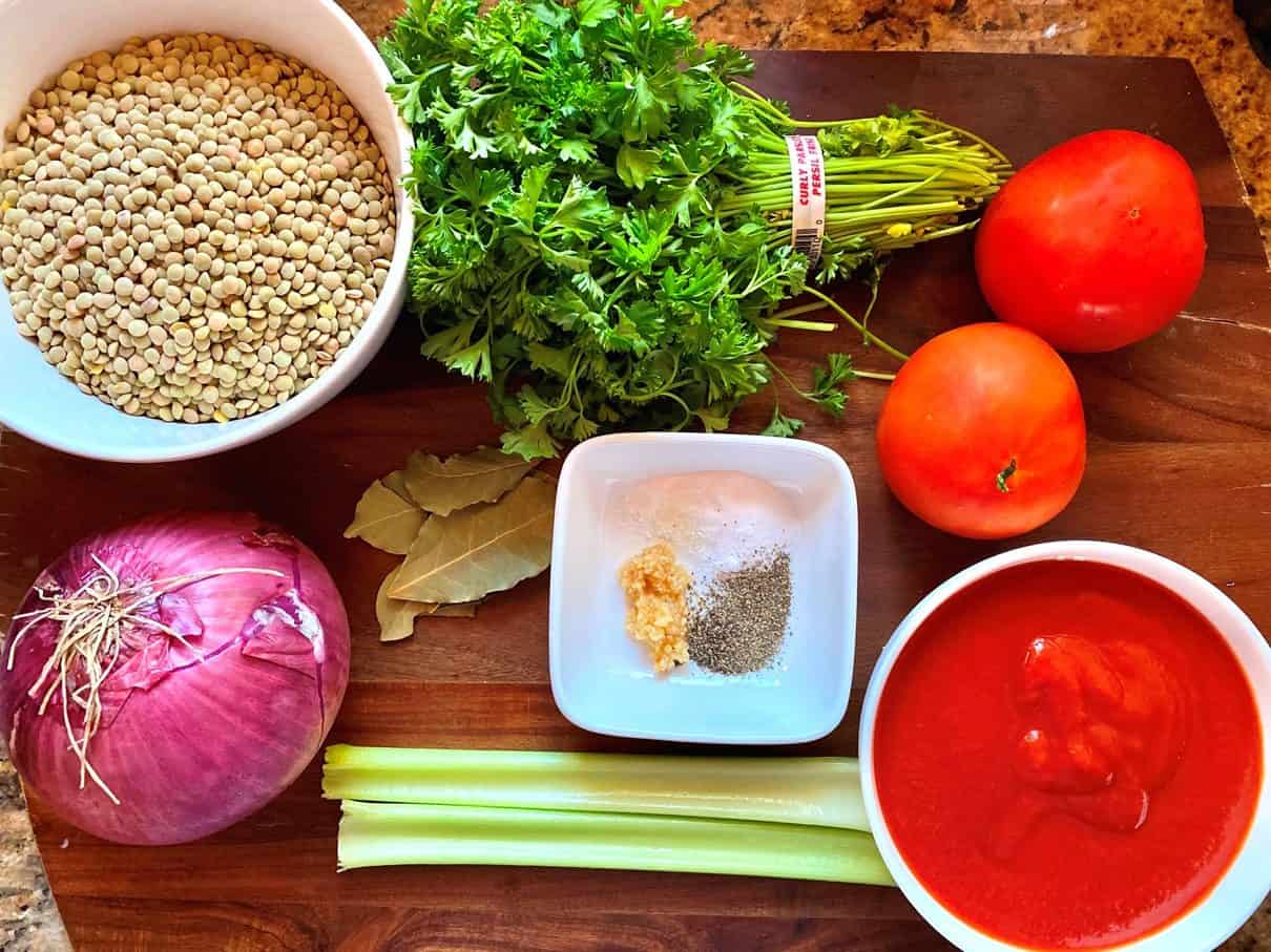 A cutting board with fresh ingredients for the lentil soup. 