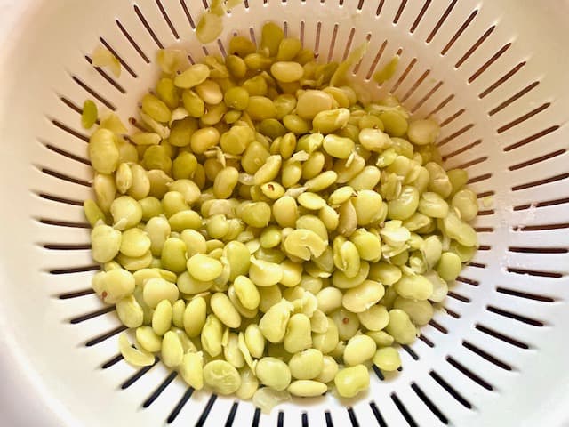 Green lima beans, cooked and shown in a colander to drain. 