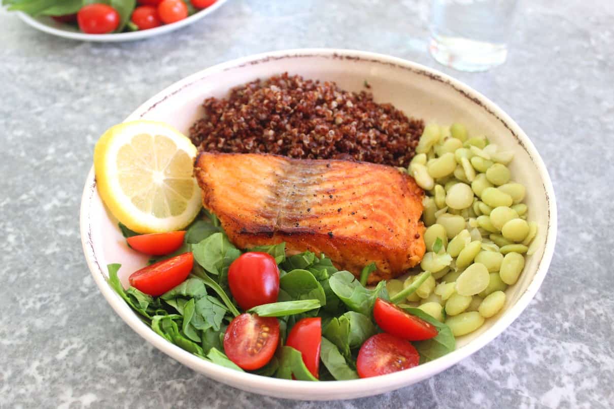 Healthy Salmon, Red Quinoa Dinner plate filled with fresh spinach, grape tomatoes and lima beans. 
