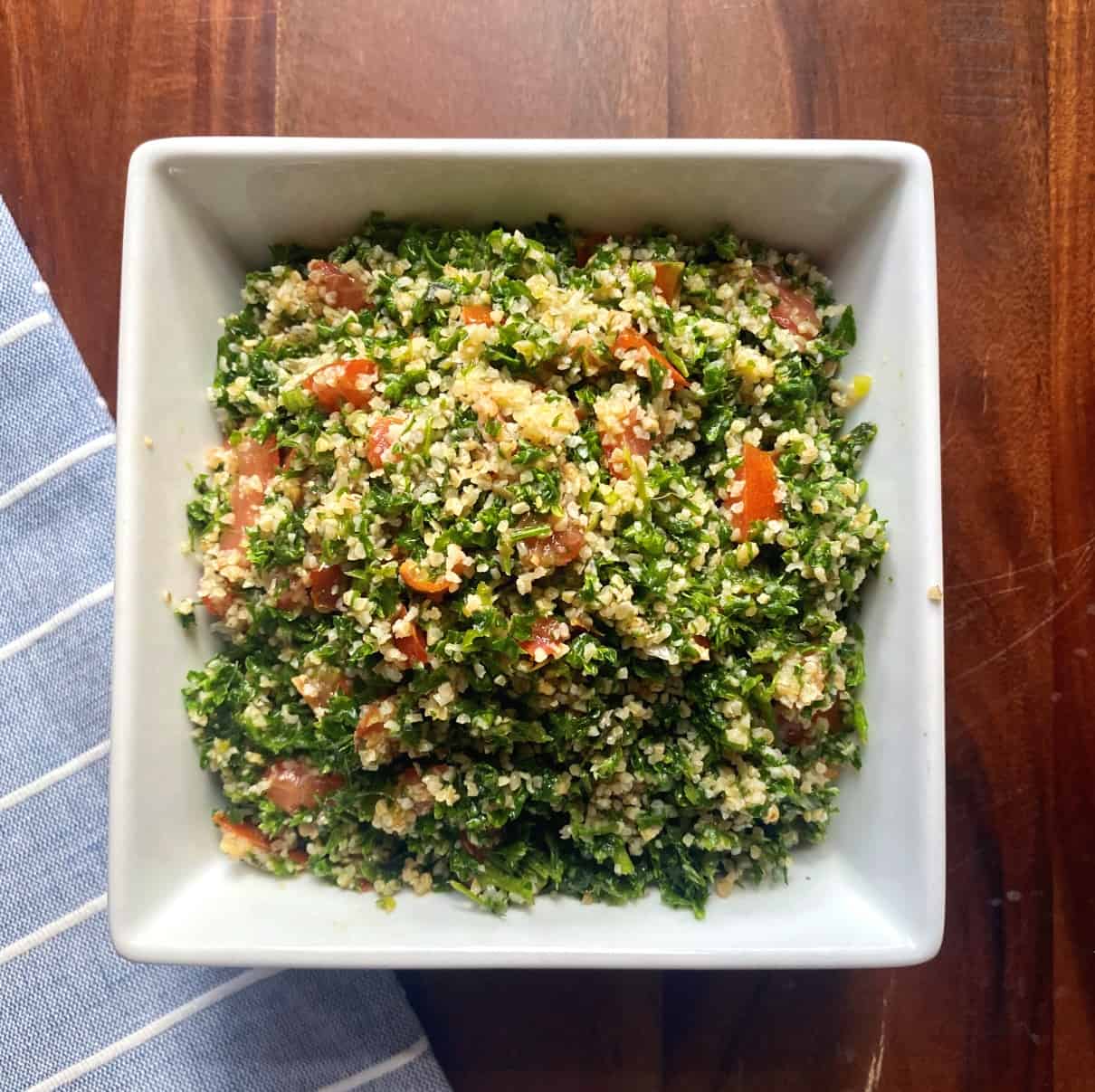 Tabouli salad chopped with an electrical food chopper. Salad is made with lots of parsley, mint, green onions, tomatoes, bulgur, lemon juice and olive oil.