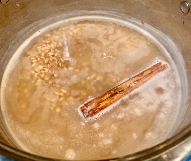 Cooking farro grains with cinnamon stick.