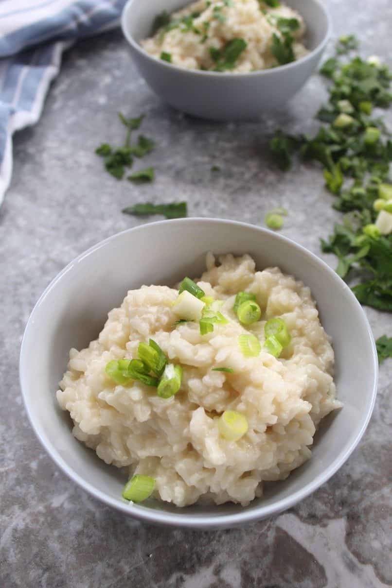 Cheese rice topped with green onions served in a bowl as a side dish.