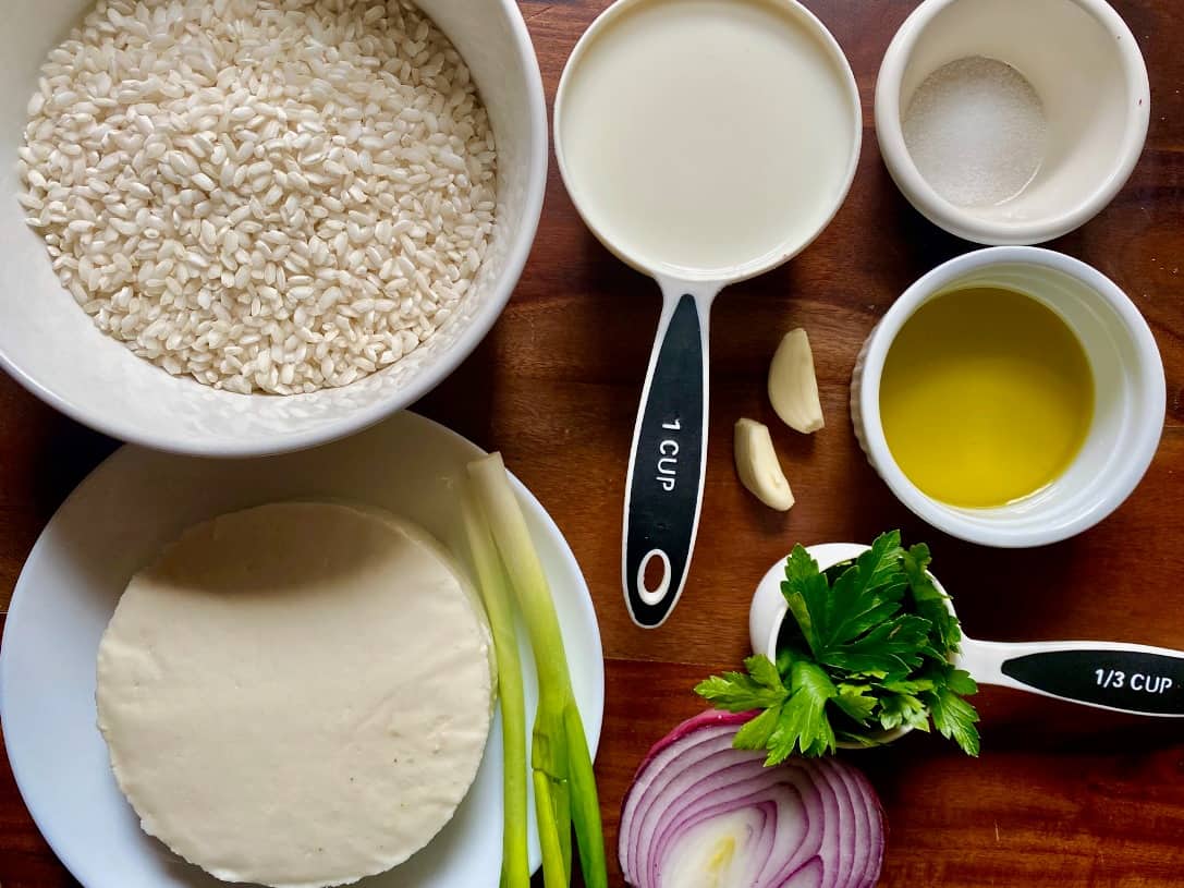 Ingredients used to cook cheese rice: pearl rice, milk, salt, queso fresco, green onions, garlic, olive oil, cilantro and red onion.