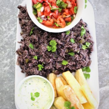 Rice & Black beans family style dinner served in a platter with a tomato based salad and fried yucca with a dip.