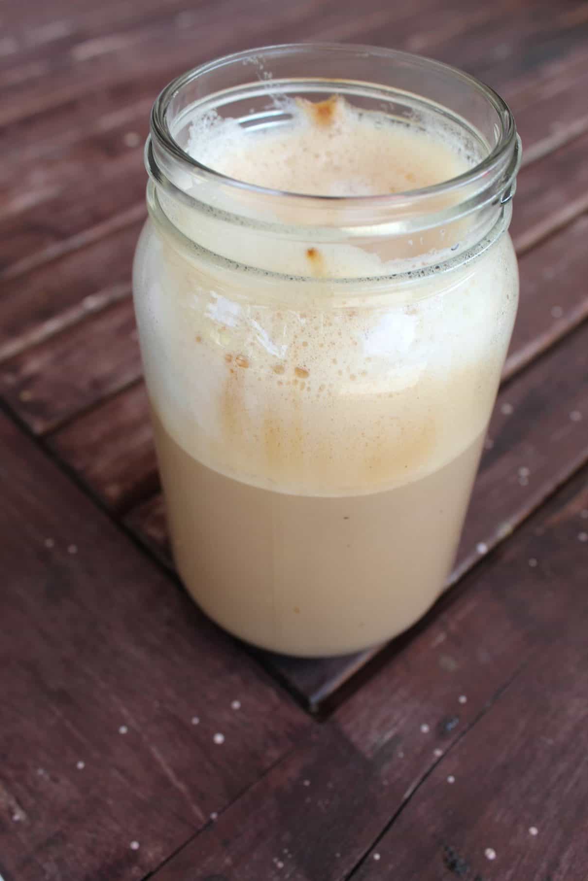 A jar of homemade latte made with frothy milk and whipped instant coffee.