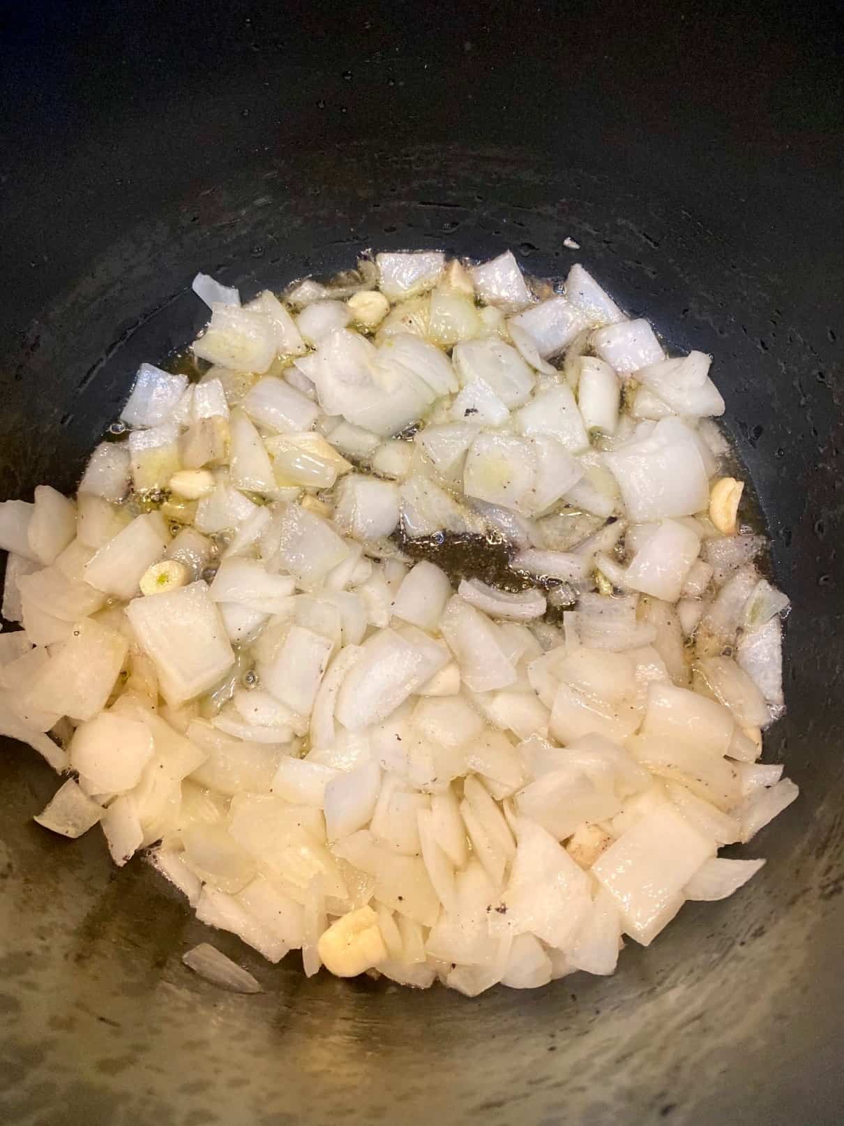 Sauteing chopped white onions and garlic in olive oil.