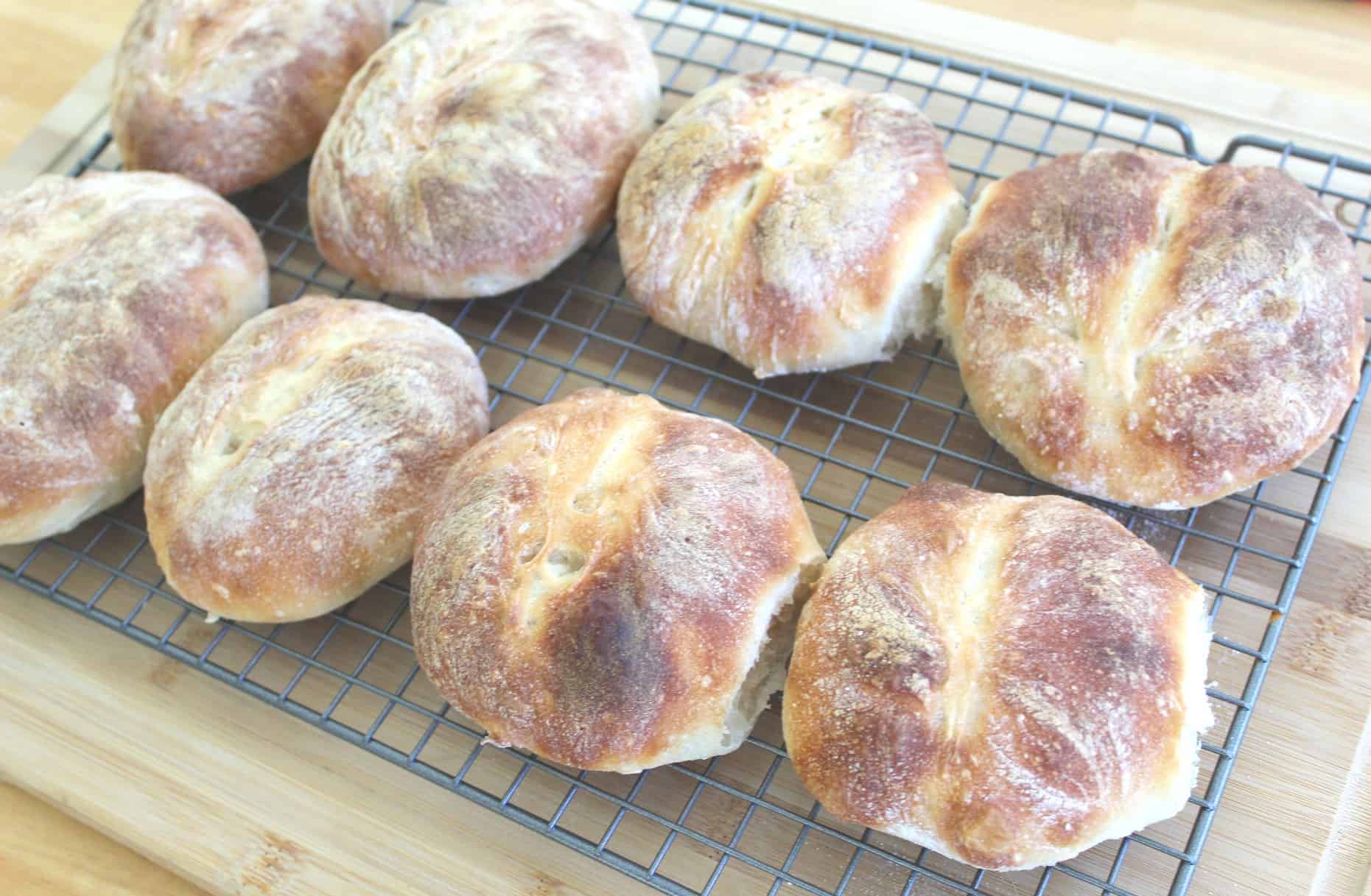 8 freshly baked breads in the cooling rack. They look uneven but with a beautiful baked crust.