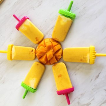 Mango popsicles in a circular shape with a cut mango in the middle