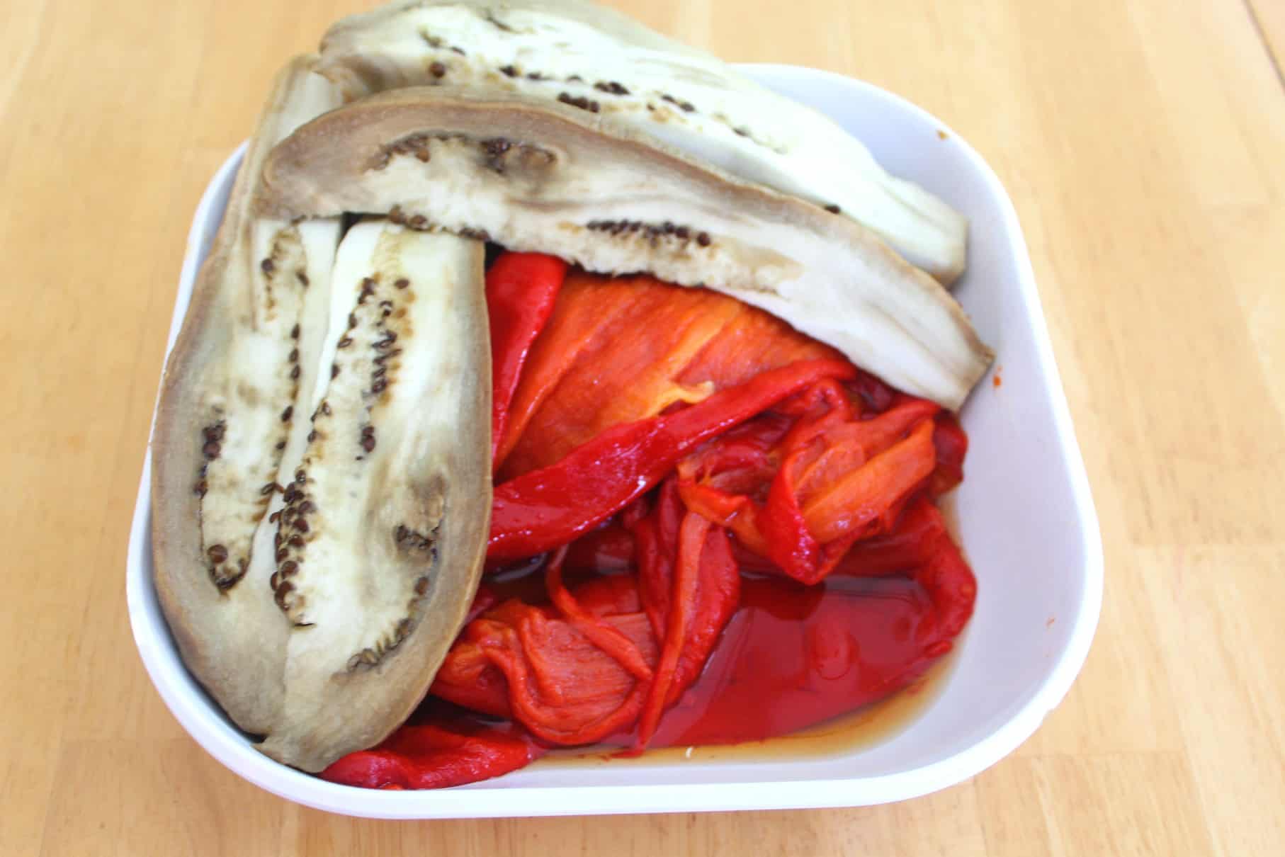 Peeled red peppers and eggplant on a plate.