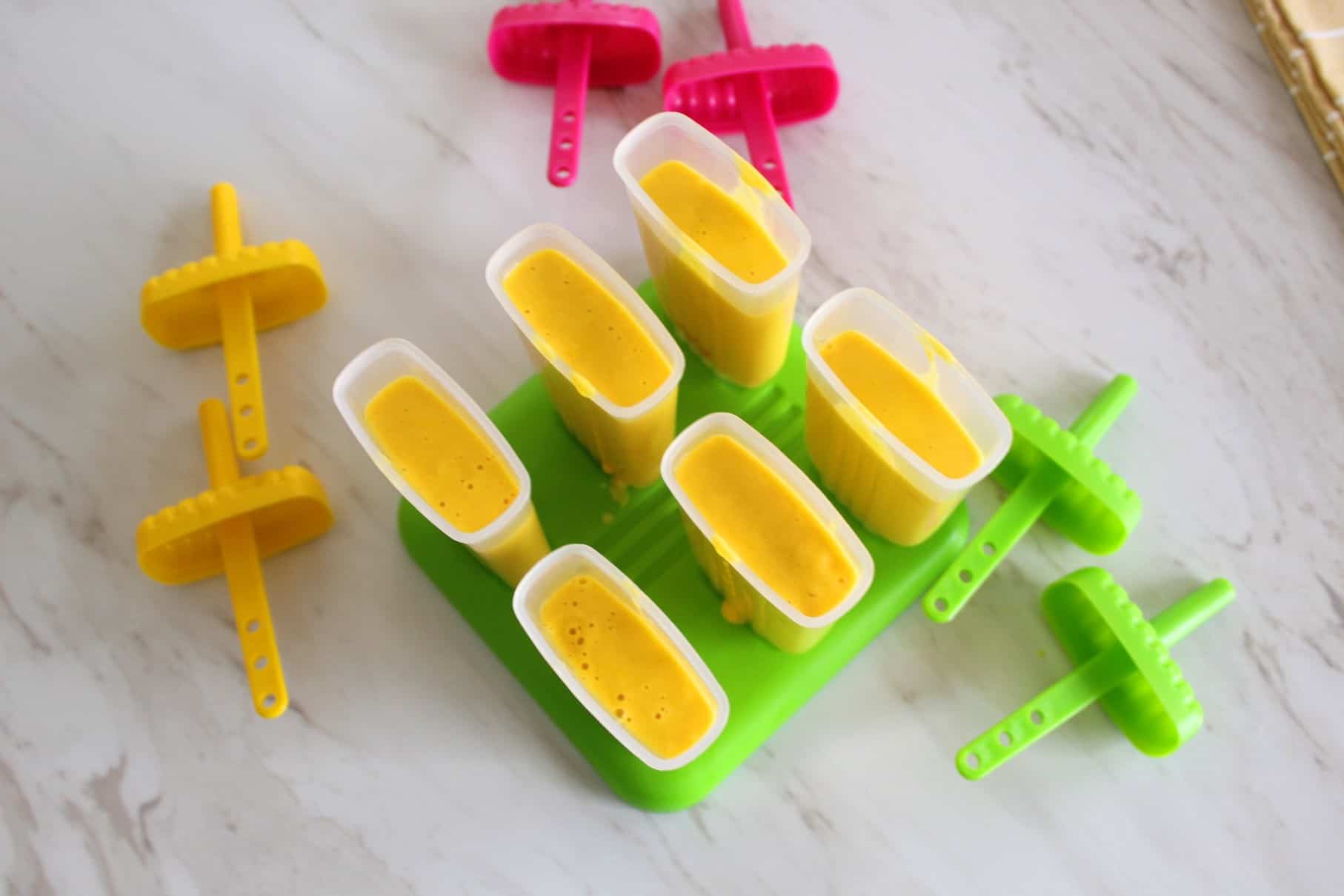 Popsicle molds filled up with the mango blend ready to be frozen.