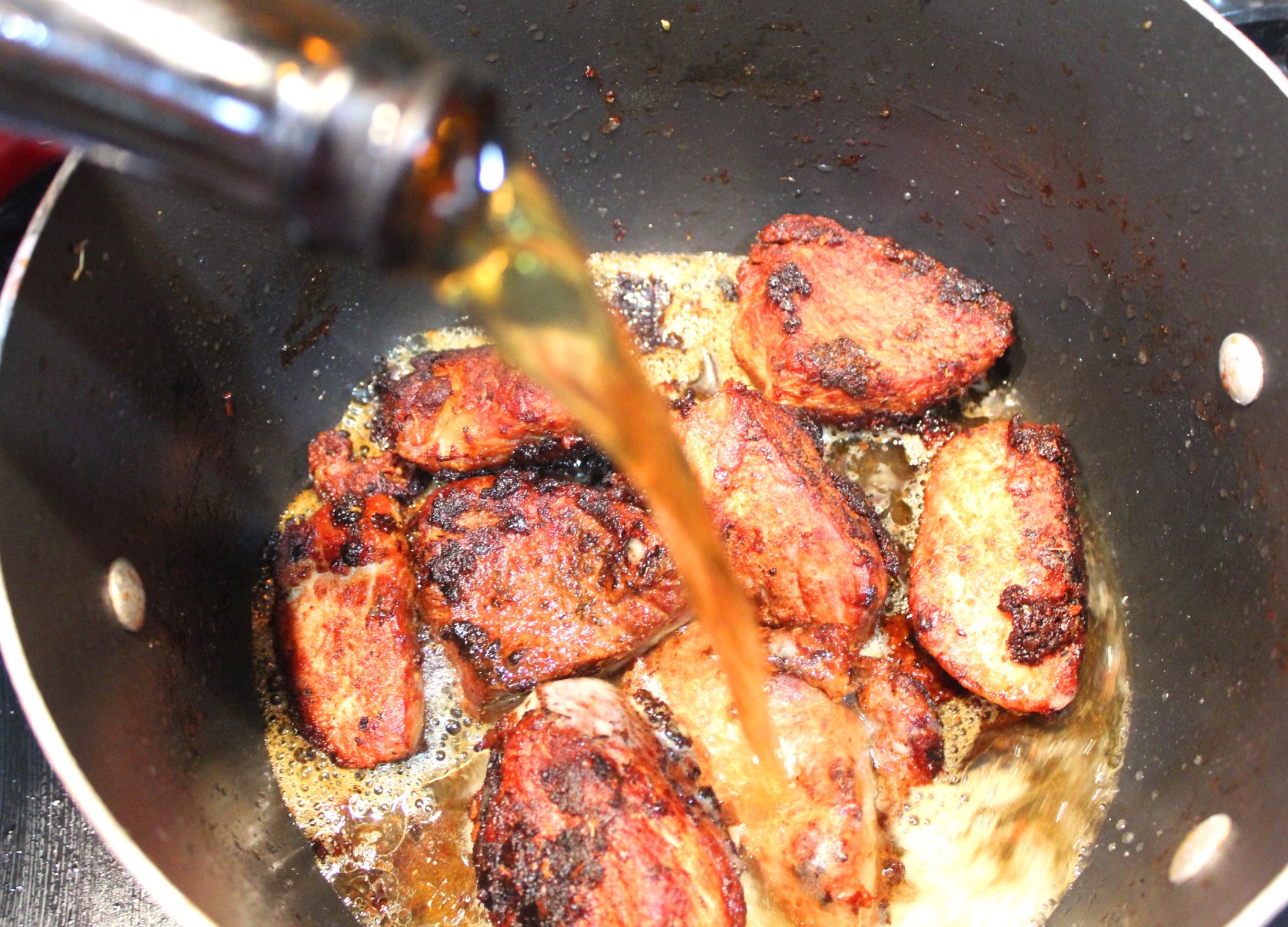 Adding beer to the pot with fried chicharron.