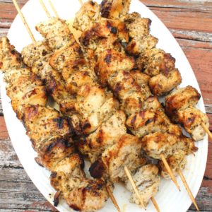 An oval platter with grilled chicken kabobs still in skewers