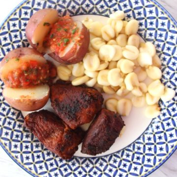 A plate with mote, potatoes with llajua and pork chicharon cooked the Bolivian way.