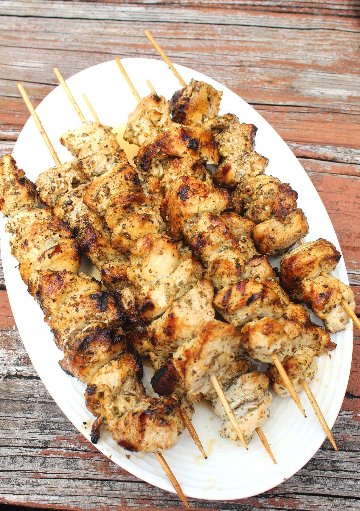 A platter full of chicken kabobs in skewers, already grilled.