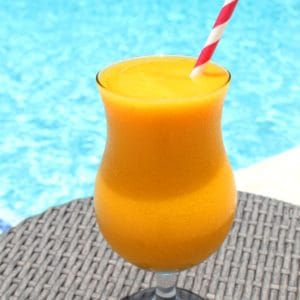A cocktail glass by the pool. Cocktail is a frozen mix of mango and passion fruit