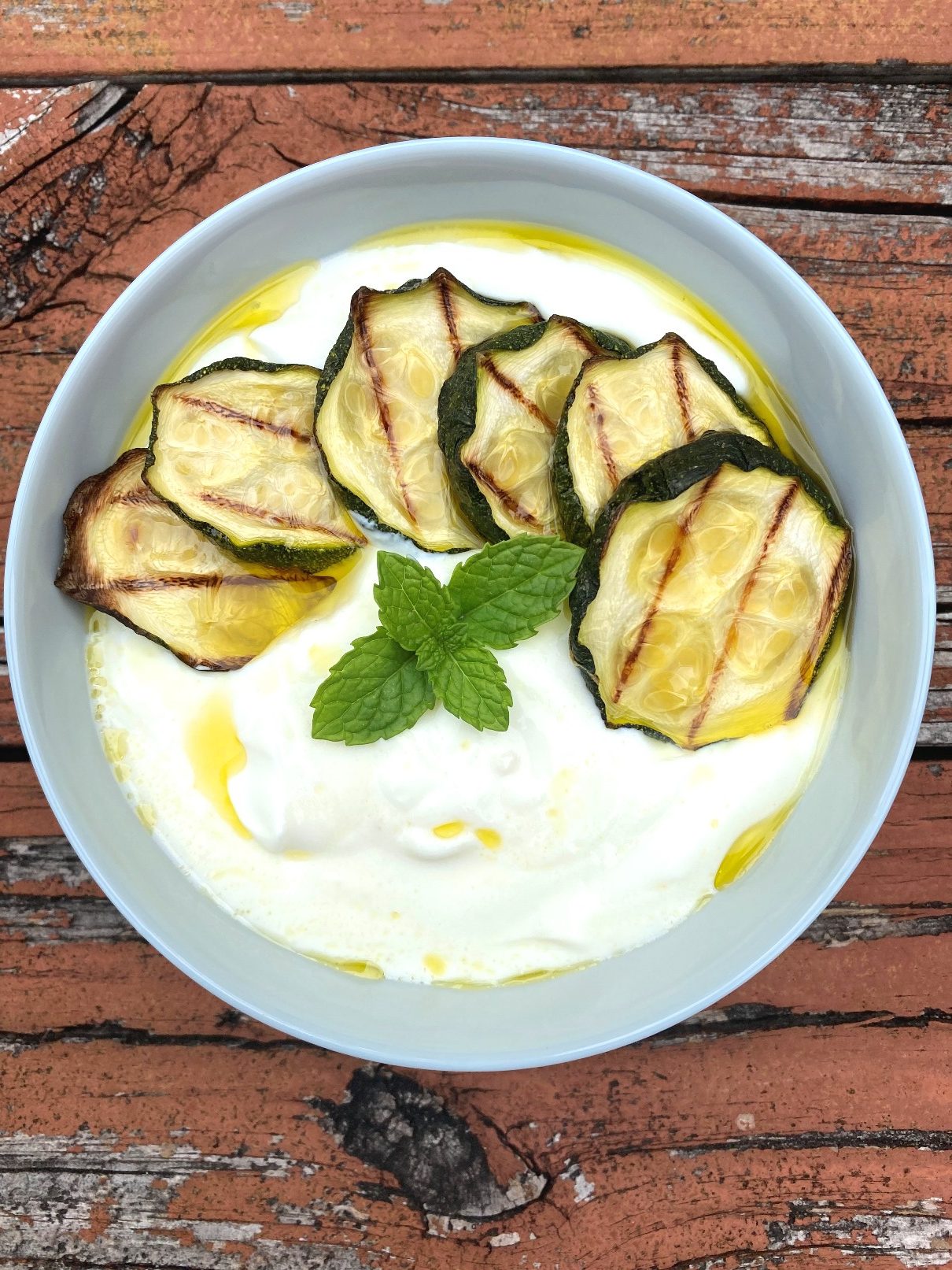 A bowl of chilled yogurt soup made with zucchini, Greek yogurt, olive oil and mint. 