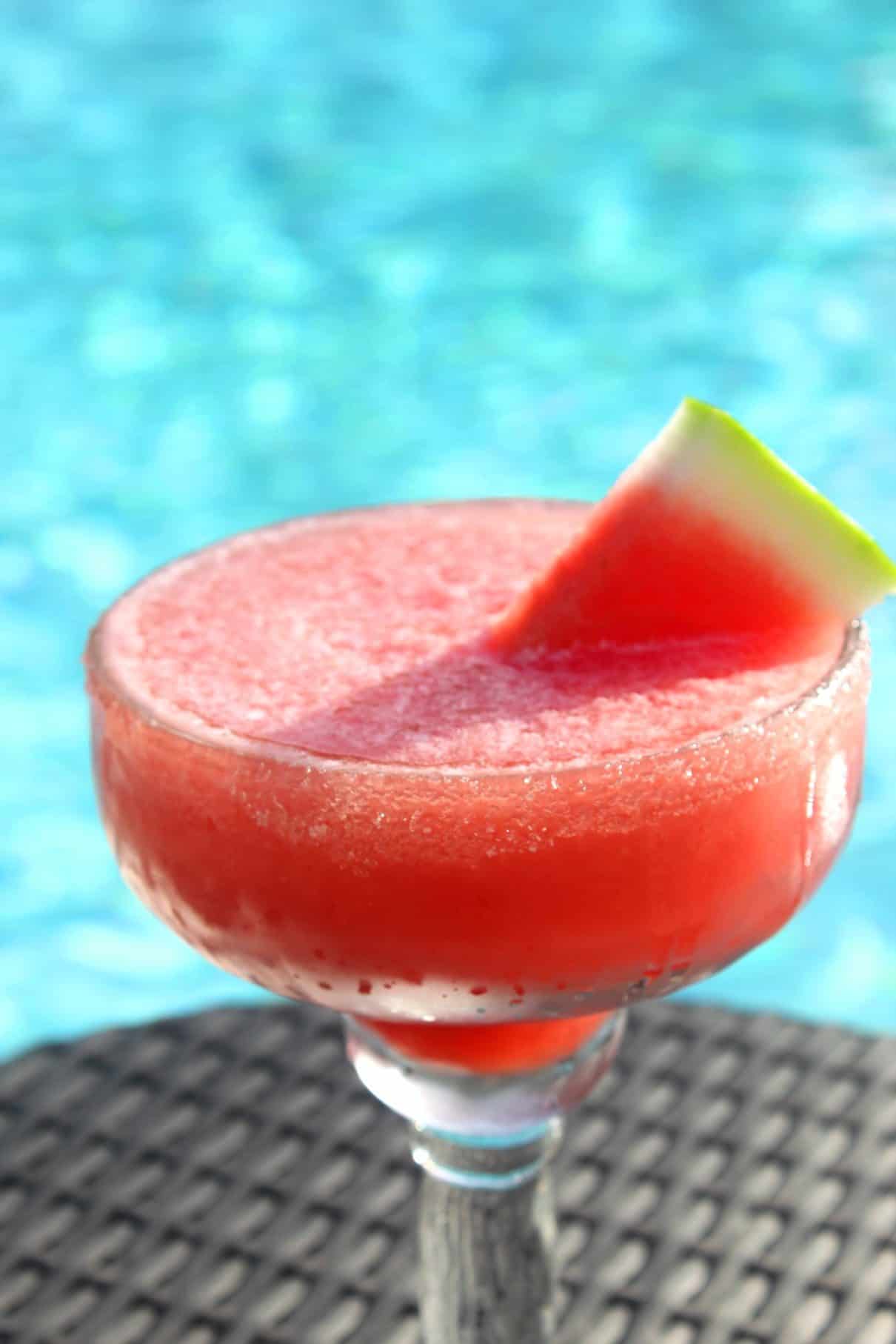 A frozen margarita drink made with watermelon and garnished with a watermelon slice, served by the pool!