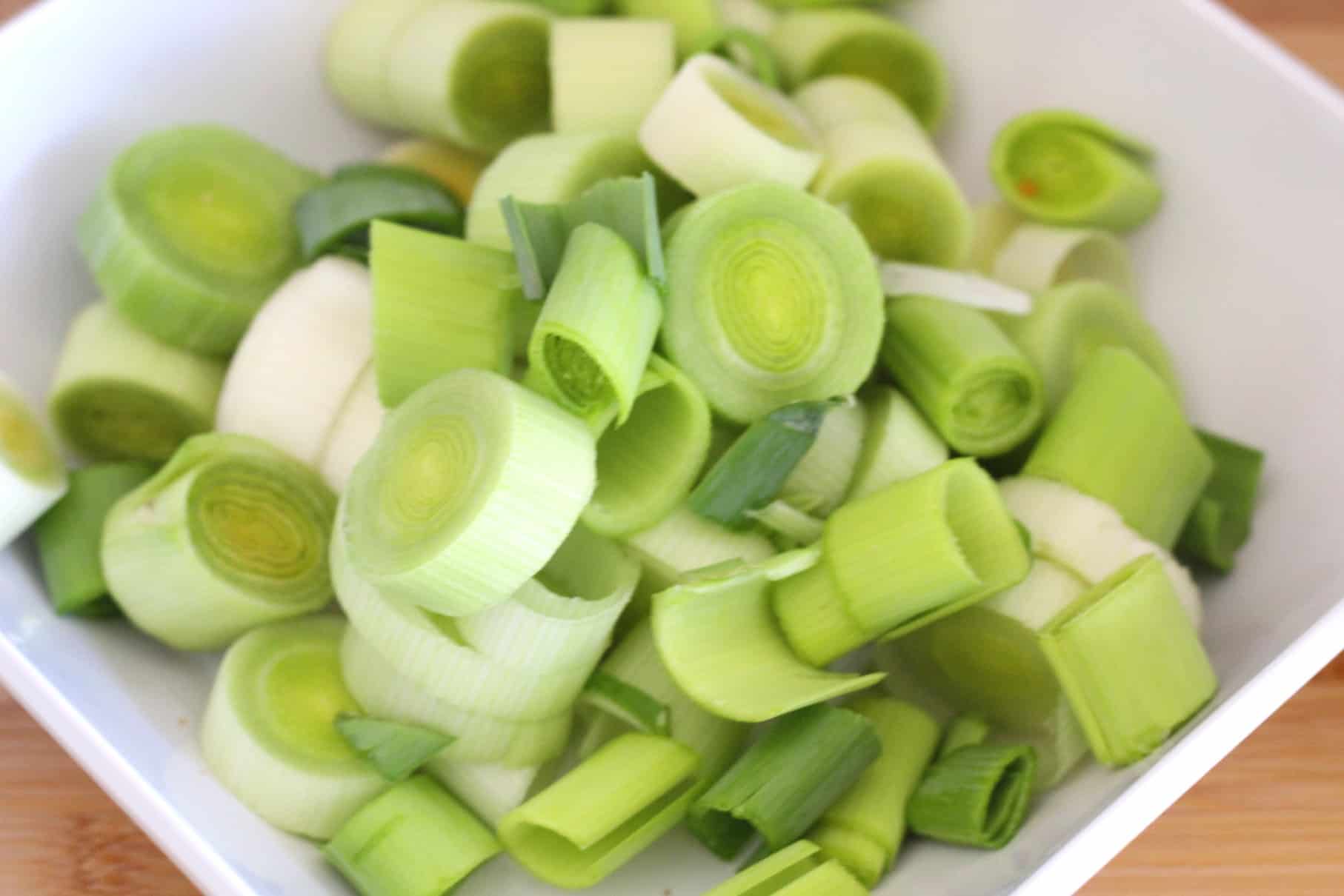 A container with chopped leeks in round shapes, like medallions.