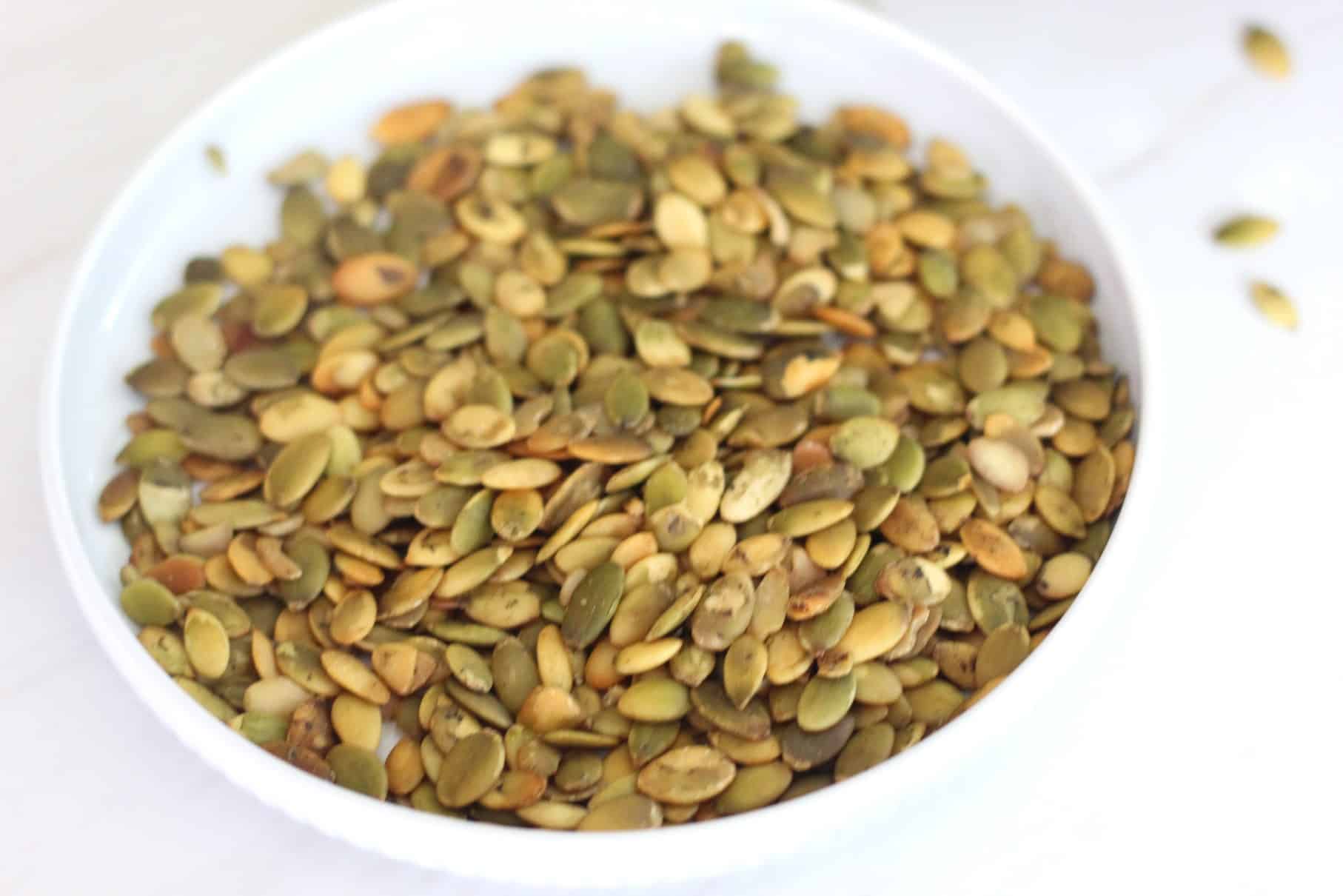 Pumpkin seeds or pepitas on a round plate. These seeds are used as a topping for the soup.