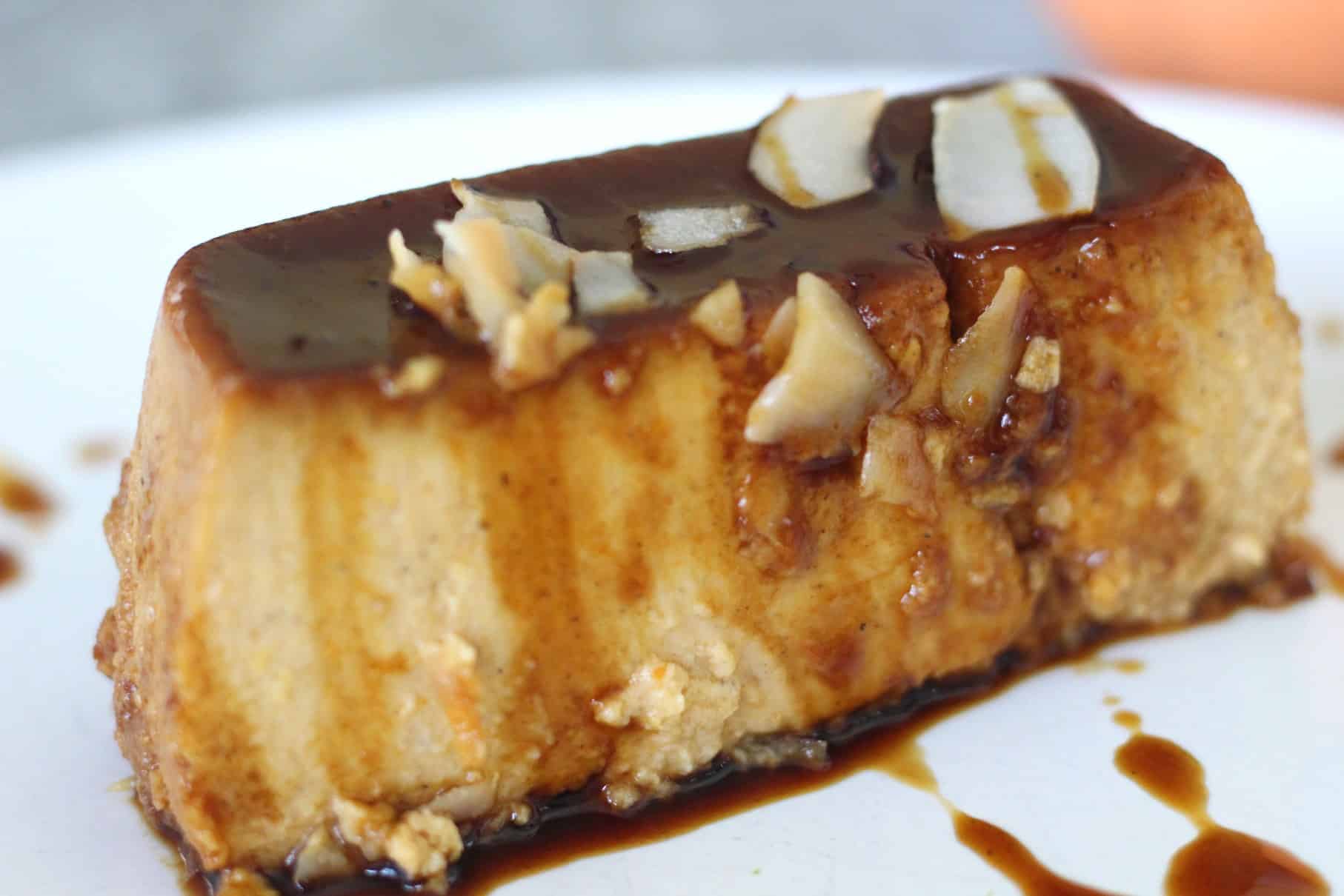 A slice of flan covered in coconut chips and drizzled with coconut sugar caramel for a darker look.