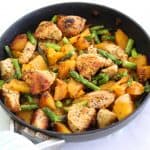 A skillet with chicken, butternut squash and asparagus