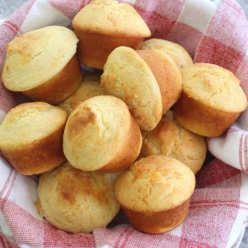 Cornbread muffins filled with cheese, over a serving basket lined with a napkin
