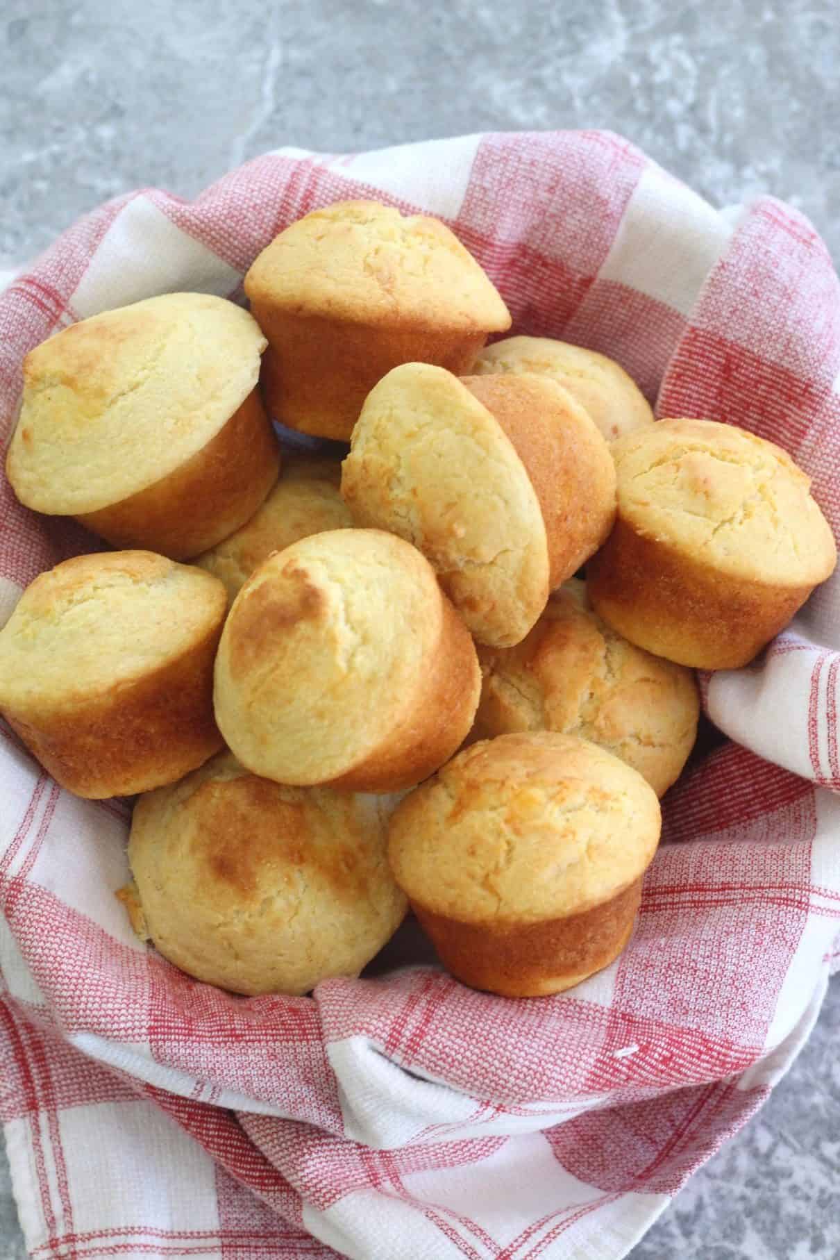 Cheese Cornbread Muffins, baked, over a serving basket lined with a kitchen napkin.