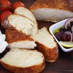 Sliced homemade bread shown with olives, tomatoes and cheese.