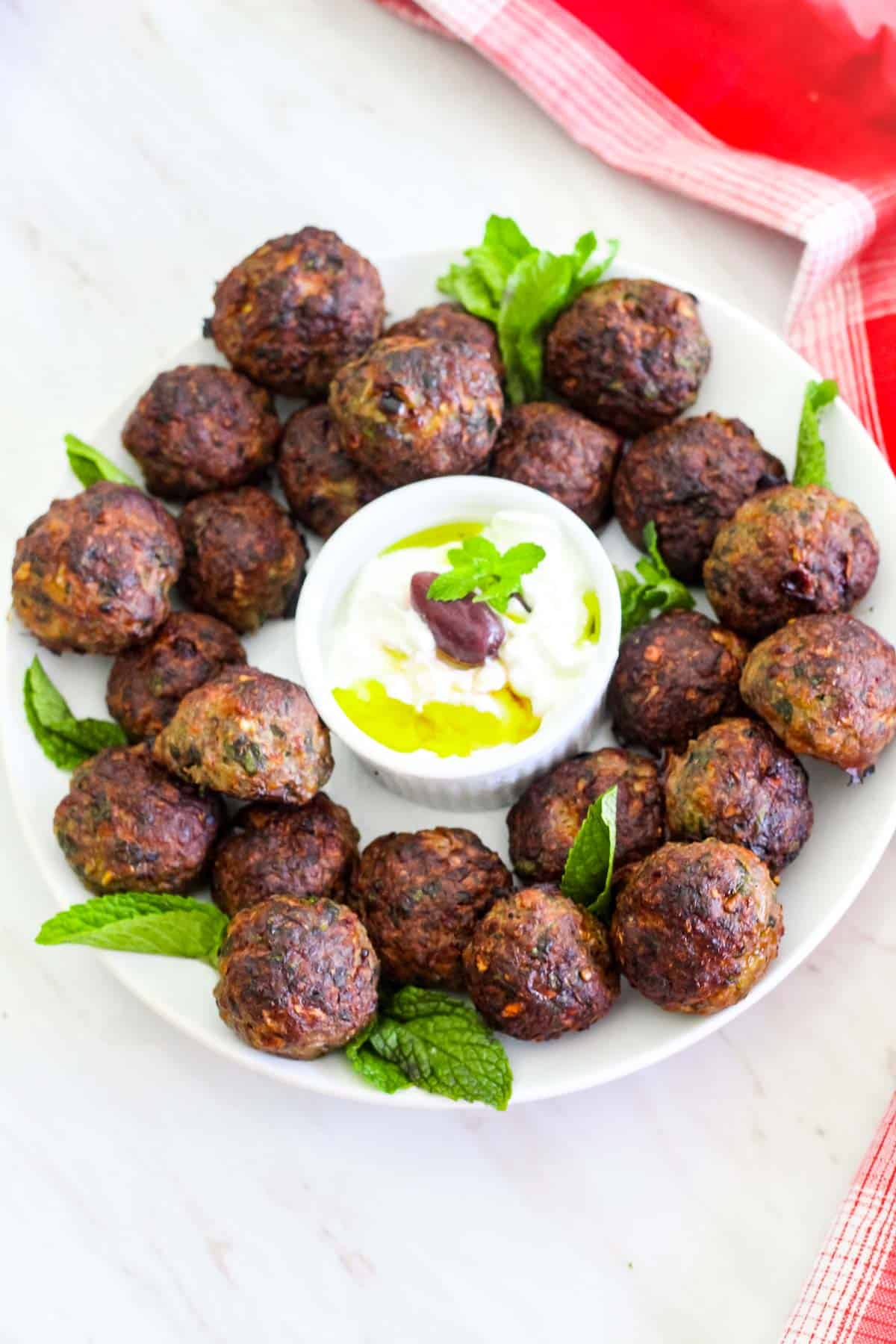 Albanian mint meatballs made with ground beef. These meatballs are called qofte and you see them served in a round platter garnished with fresh mint and a yogurt based dip.