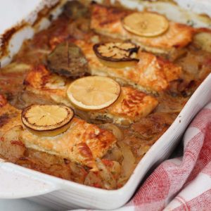 Baked dish with salmon and onions. Salmon is garnished with lemon.
