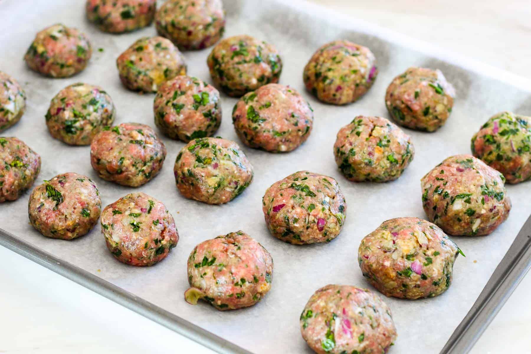 Unbaked mint meatballs before going in the oven. They're lined up in a tray.