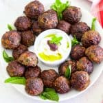Qofte - mint meatballs in a platter, garnished with mint and yogurt dip.