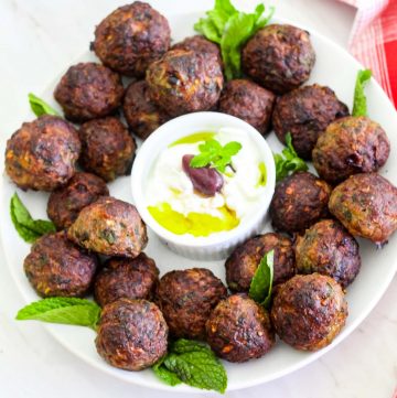 Qofte - mint meatballs in a platter, garnished with mint and yogurt dip.