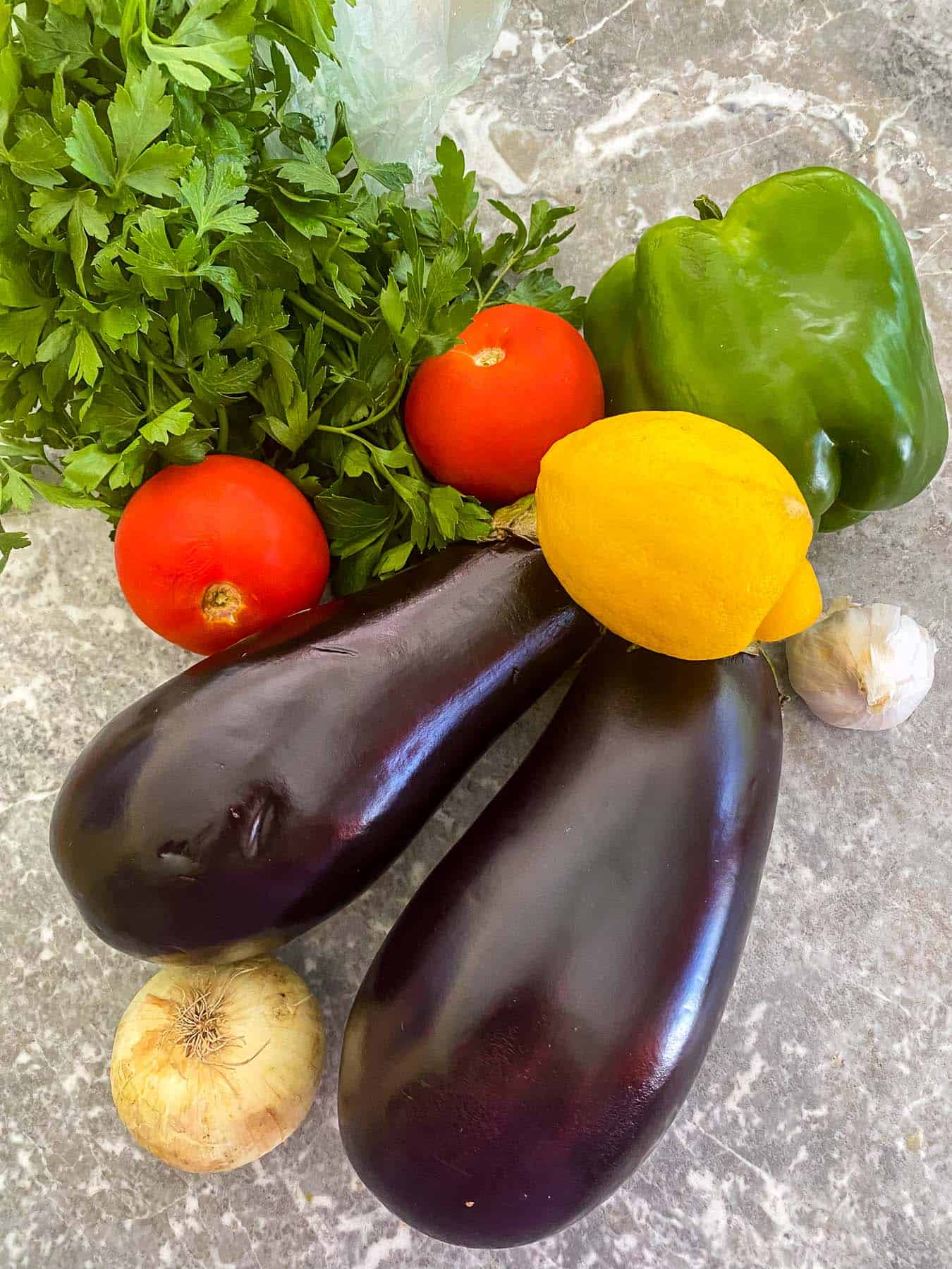 Fresh ingredients used to make the relish: eggplants, bell pepper, tomatoes, parsley, lemon, onion and garlic. Other ingredients like olive oil or seasonings are not shown in the picture. 