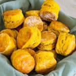 Pumpkin biscuits on a serving basket lined with a green napkin.