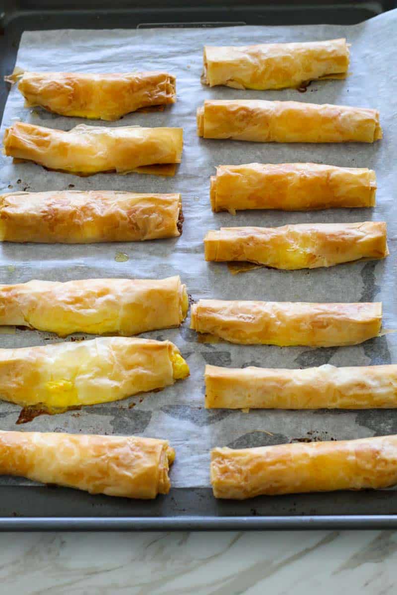 A baking tray, lined with parchment paper showing just baked phyllo sticks right out of the oven. 