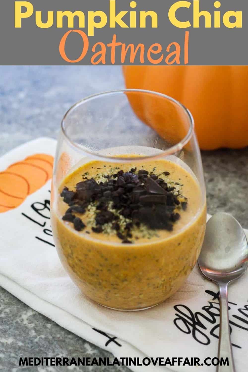 Pumpkin Chia Oatmeal topped with dark chocolate. Oatmeal is served over a clear glass placed on a towel, next to a spoon. Image has a title bar and the website link at the bottom.