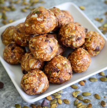Pumpkin seeds energy bites, piled on a pyramid shape on a square serving dish.