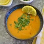 Bowl of creamy soup, garnished with parsley and lemon.